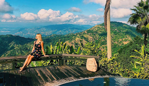 Woman sitting on a balcony overlooking tree-covered mountains