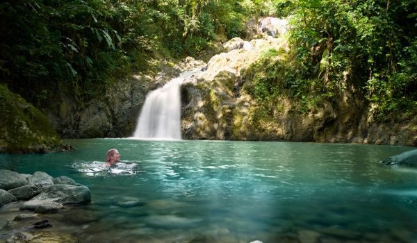 Femme se baignant dans le bassin au pied de la chute d'eau