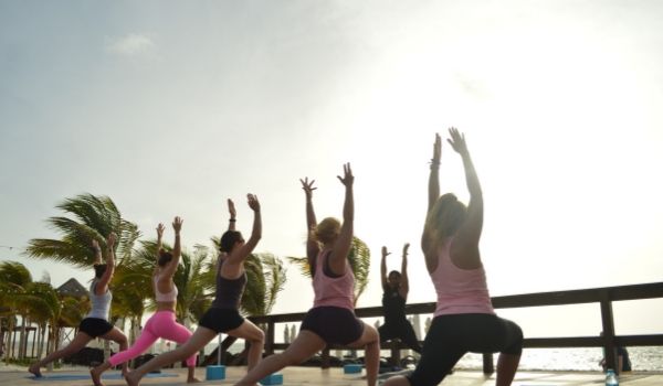 Group of people doing sunrise yoga by the beach