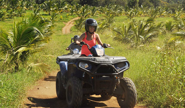 Woman riding an ATV surrounded by lush greenery