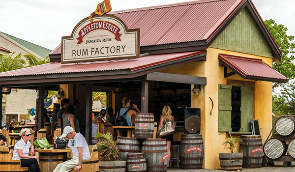 Personnes assises à l’extérieur d’une distillerie de rhum à des tables et des chaises faites de barils