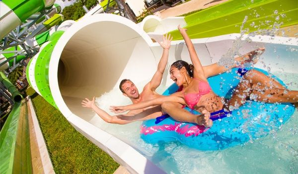 Man and woman riding inner tube down water slide