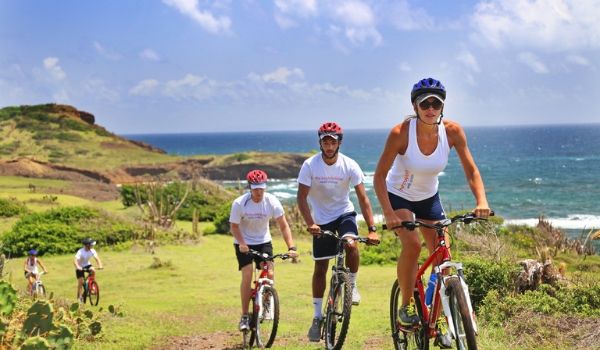 People bike riding up a hill overlooking the coast