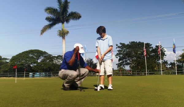 Un homme apprenant un à jeune garçon comment golfer