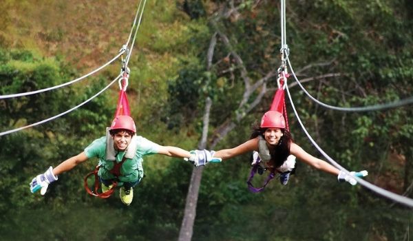 Deux enfants se tenant la main en faisant de la tyrolienne dans la forêt
