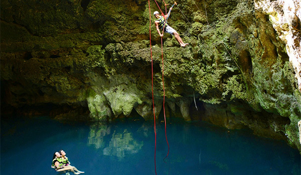 Femme faisant de la spéléologie dans une grotte souterraine inondée