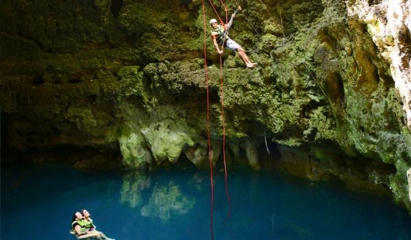 Femme faisant de la spéléologie dans une grotte souterraine inondée