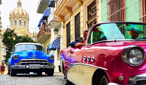 Two classic car driving through the streets of Havana