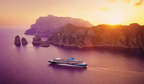 Vue aérienne du bateau de croisière naviguant près de paysages rocheux au coucher de soleil