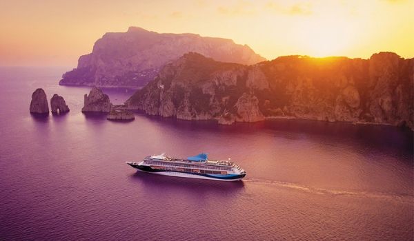 Vue aérienne du bateau de croisière naviguant près de paysages rocheux au coucher de soleil
