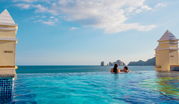 Couple relaxant dans une piscine à débordement donnant sur les arches de Los Cabos