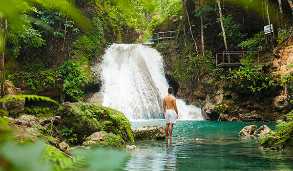Man standing by a waterfall in the jungle