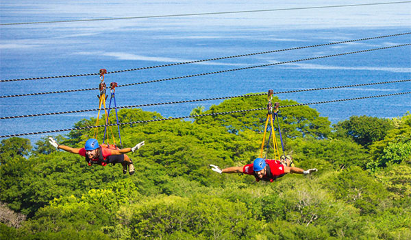 Two people ziplining above the jungle