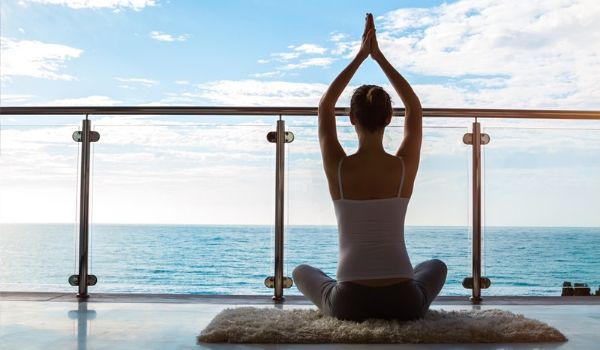 Femme faisant du yoga sur un balcon surplombant la mer