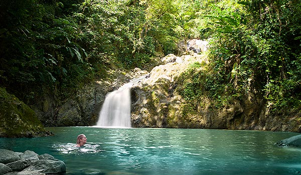 Femme se baignant dans un bassin paisible au pied d’une cascade