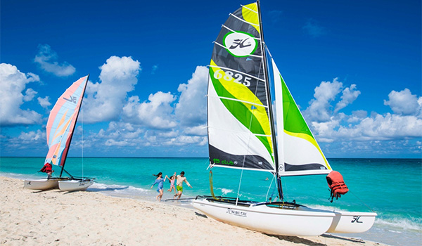 Famille jouant sur la plage devant un splendide catamaran
