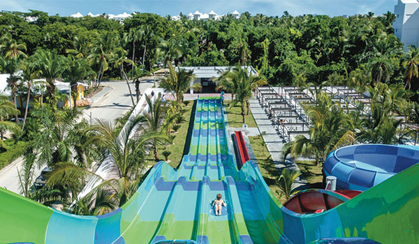 View from the top of a four-lane water slide as a person zooms down to the bottom