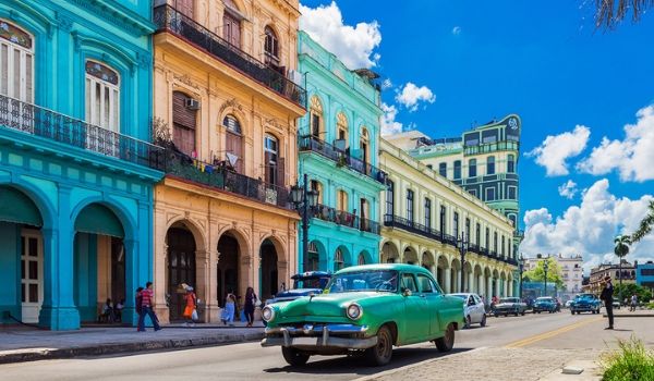 Classic American car driving past colonial buildings in Havana