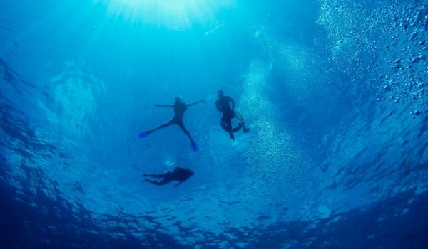 Three people scuba diving in the blue waters of Cancun