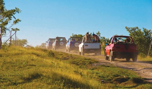 Convoy of open-air Jeeps driving down a trail in the Cuban countryside
