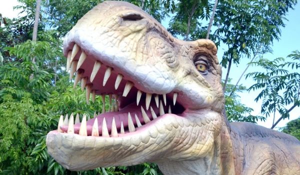 Animatronic dinosaur with its mouth open in a forest