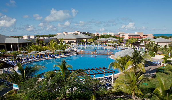 Piscine entourée de palmiers et de bâtiments