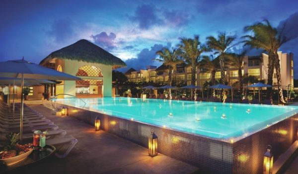 Pool lit up at night with drinks by a lounger