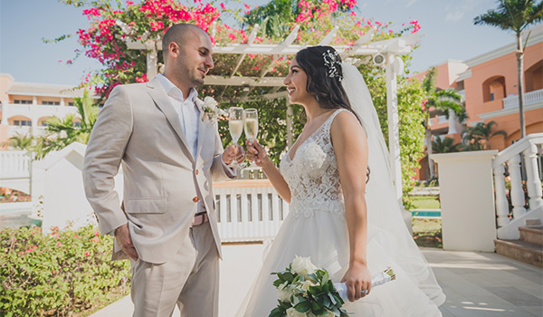 Bride and groom holding champagne glasses in a garden