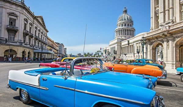 A bright blue classic car parked on a historic street in Havana