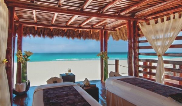 Two massage tables under a palapa right on the beach
