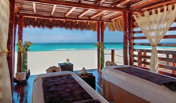 Deux tables de massage sous un palapa à la plage