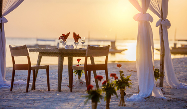 Une table et deux chaises installées pour un souper romantique sur une belle plage