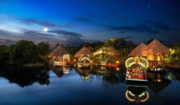 River boats cruising down a hut-lined waterway at night