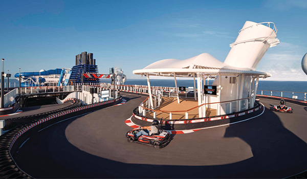 People racing in mini go karts on the top deck of a cruise ship