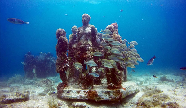 Statues sous-marines entourées de poissons