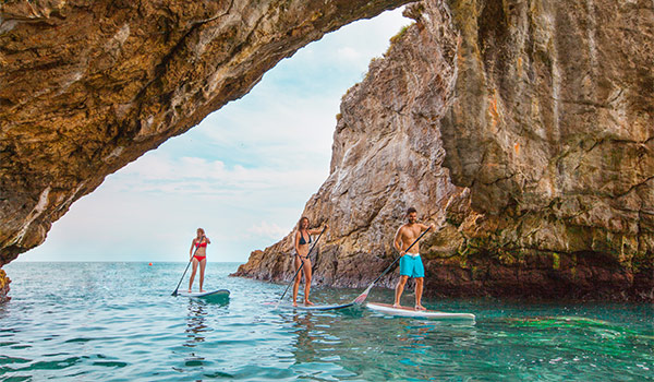 Three people paddle boarding through a cove