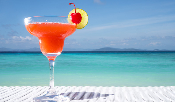 Boisson rose dans un verre à cocktail sur une table surplombant la mer