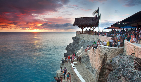 Personnes regardant le coucher de soleil depuis une falaise au Rick’s Café