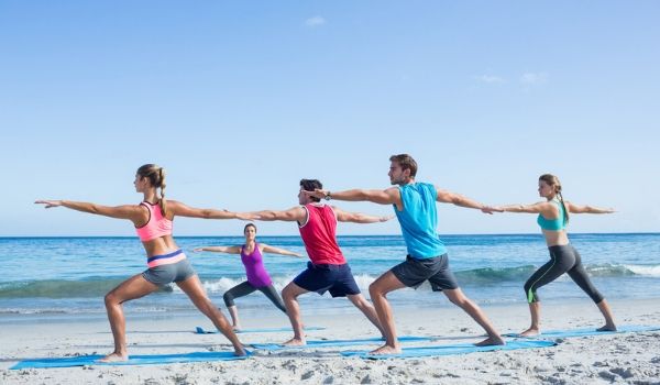 Groupe de personnes faisant du yoga sur la plage