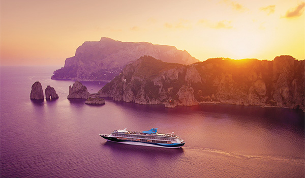 Navire de croisière au largue d'une île au coucher du soleil