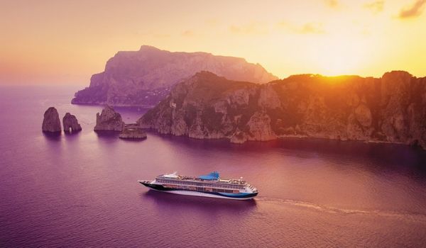 Cruise ship sailing past an island at sunset