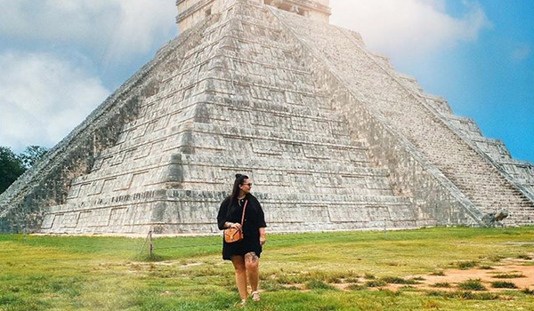 Woman standing in front of an ancient Mayan temple