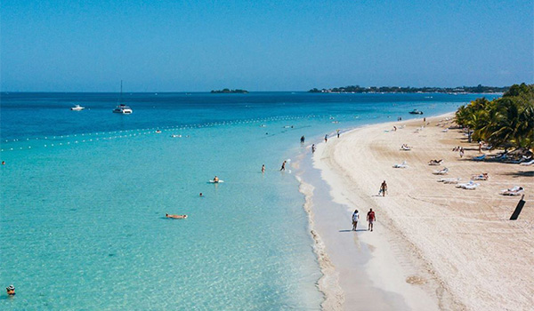 Aerial view of people walking along a white-sand beach