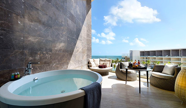 Jacuzzi on a sprawling balcony with several chairs overlooking the ocean
