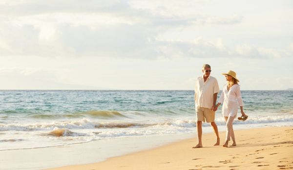 Elderly couple walking hand-in-hand along the beach