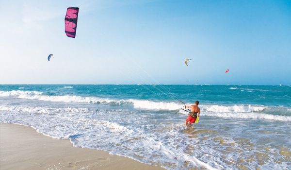 Person kite surfing by the beach