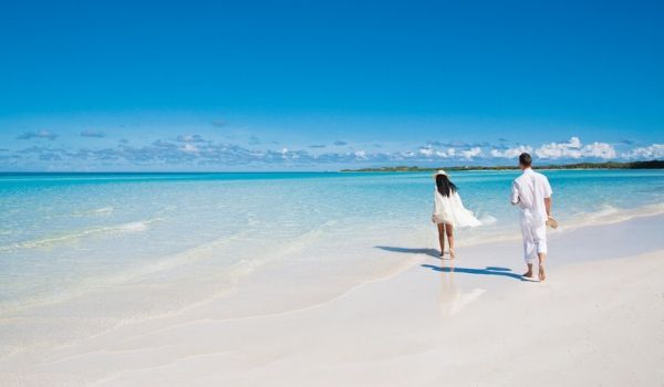 Couple walking down a pristine white-sand beach
