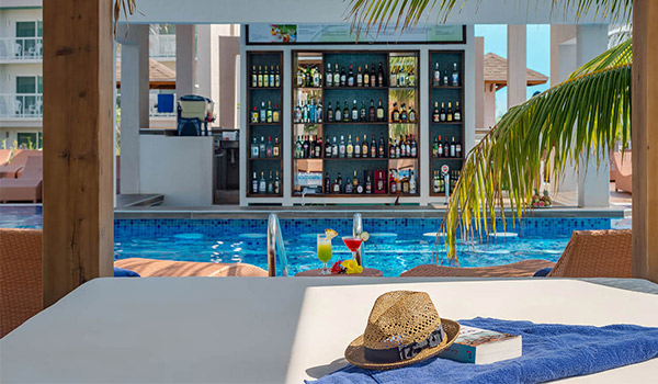 Hat and book on a shaded Bali bed overlooking a swim-up bar