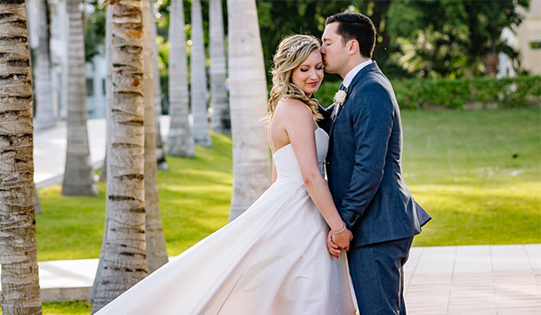 Groom and bride posing in a garden surrounded by palm trees