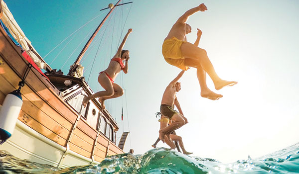 Vue du dessous d’un groupe de personnes sautant d’un bateau dans l’eau
